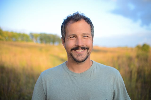 Man stands in a prairie for a portrait.