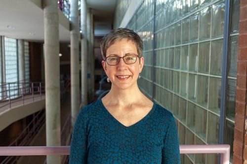 Woman stands in an atrium while posing for a photo.