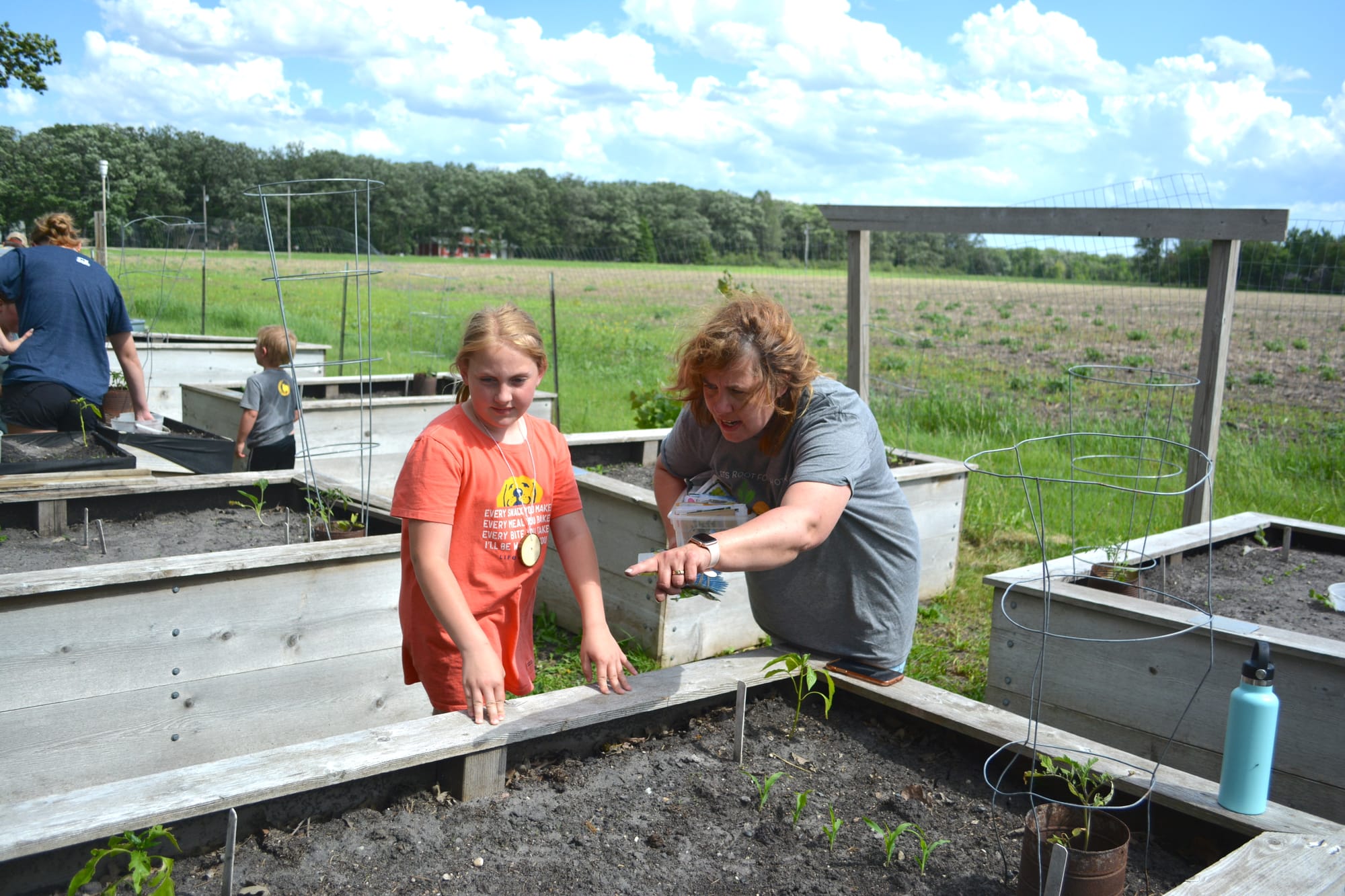 Girl listens to woman offer advice on a raised garden bed. 