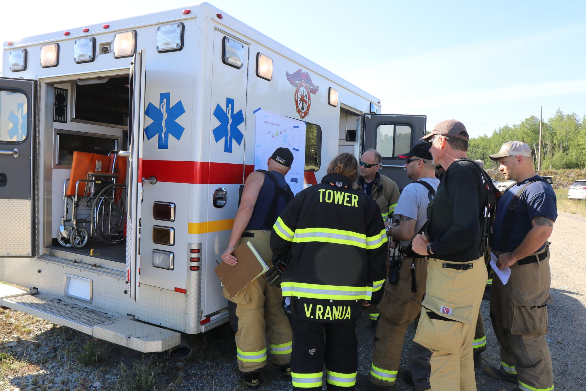 Volunteer firefighters gather around a rescue squad to look at a map during a training session.