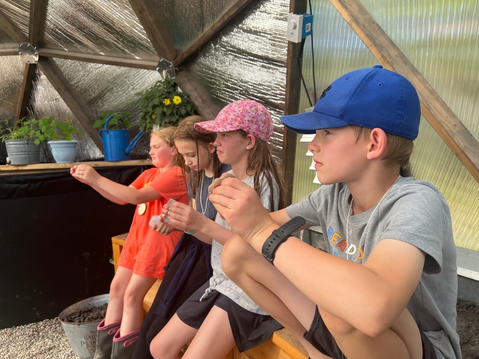 Four children hold pieces of hard plastic used to build a biodome. 