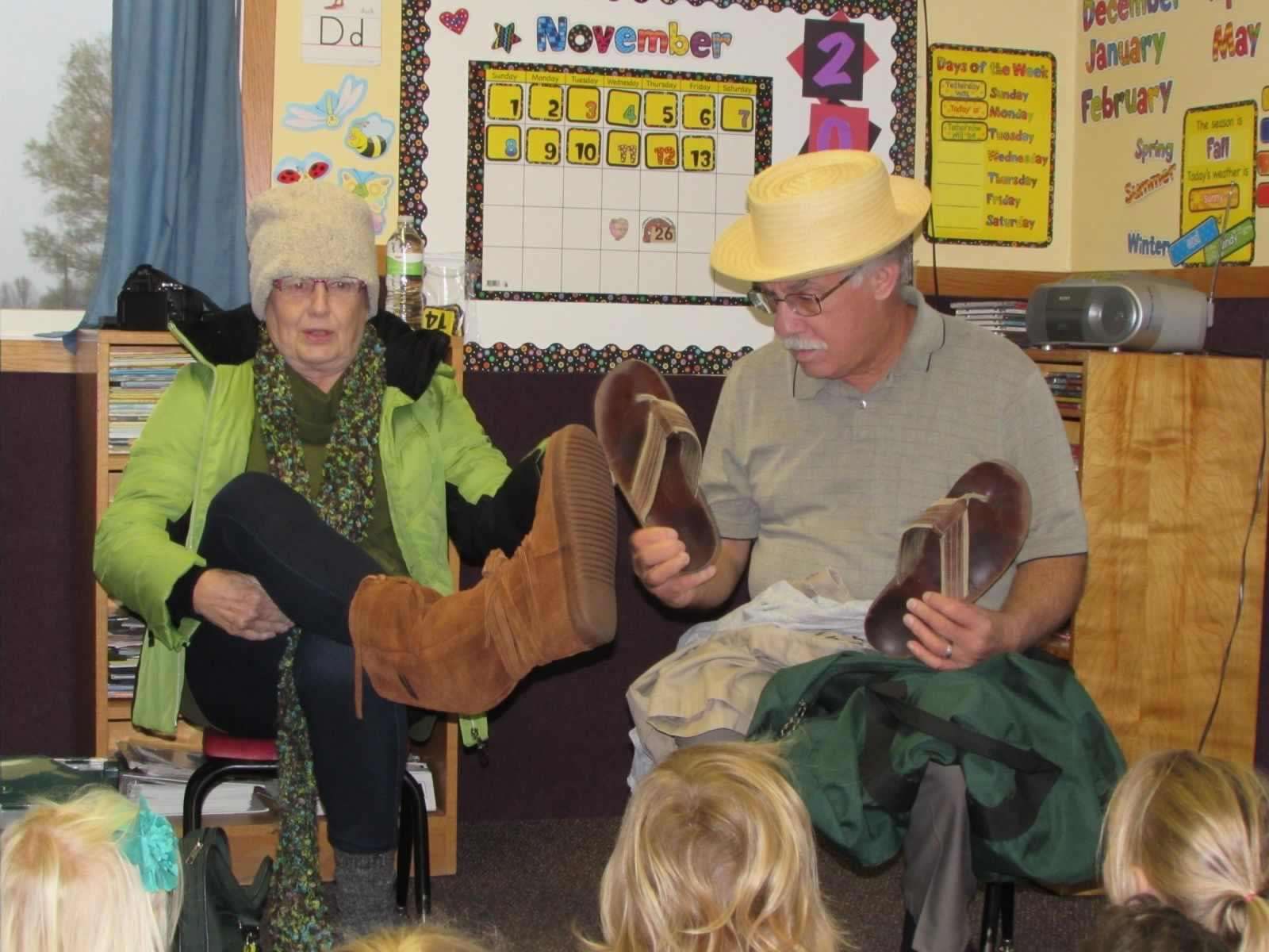 Woman dressed in winter clothes sits next to a man dressed in summer clothes for lesson on dressing for the weather.