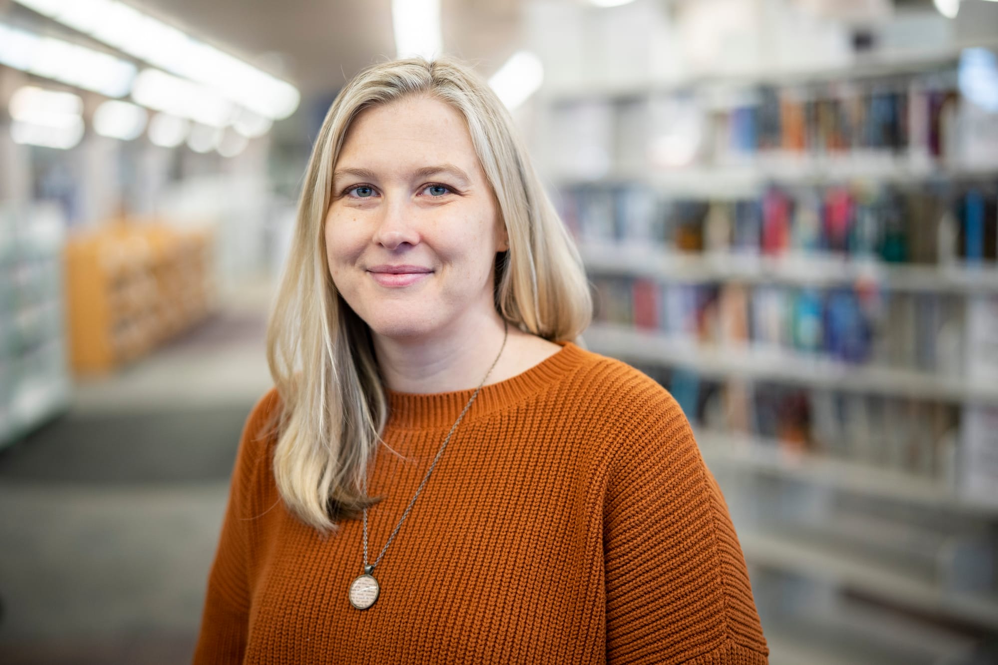 Woman poses for a portrait in a library. 