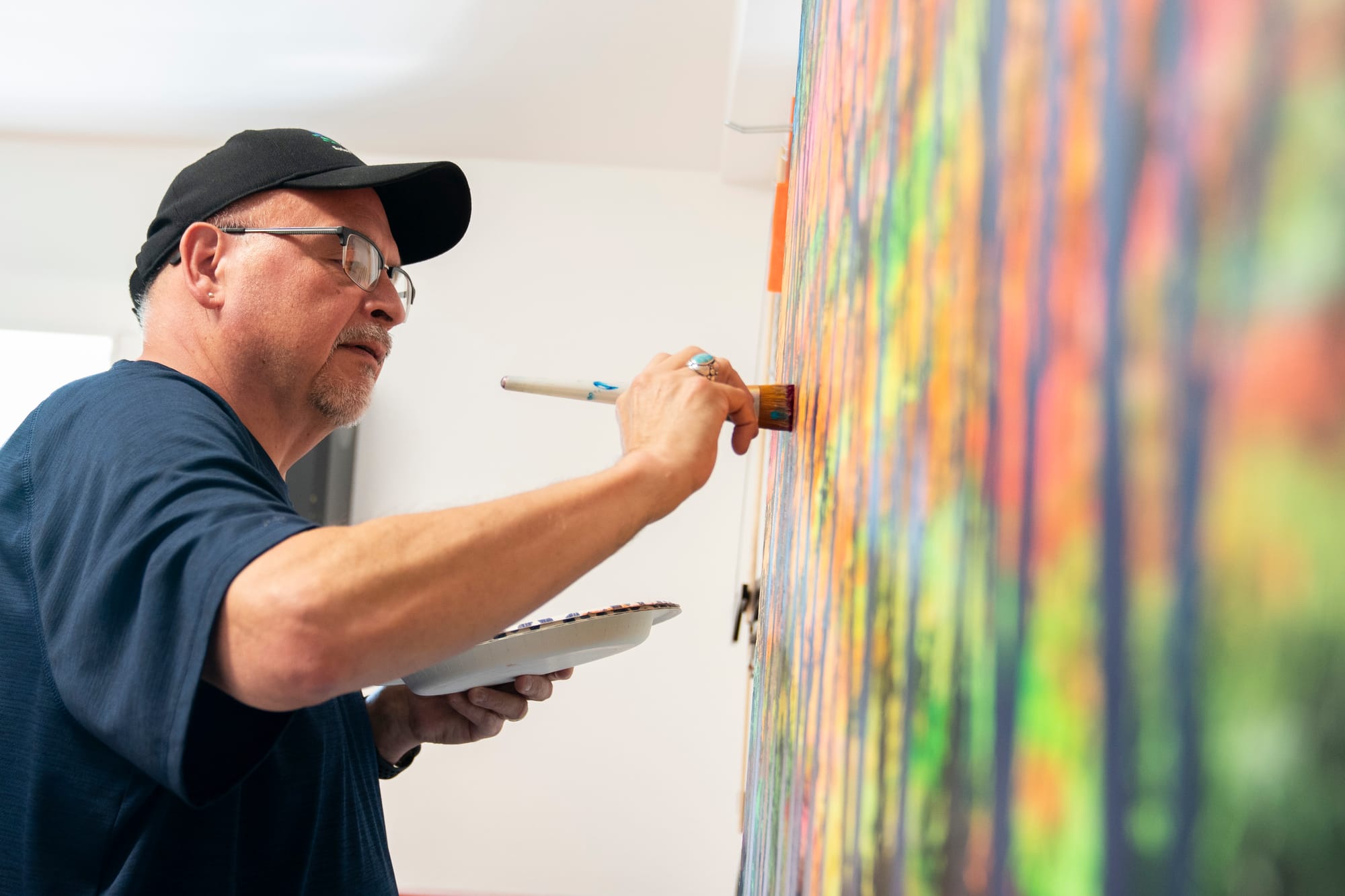 Man adds paint to a canvas with a paintbrush. 