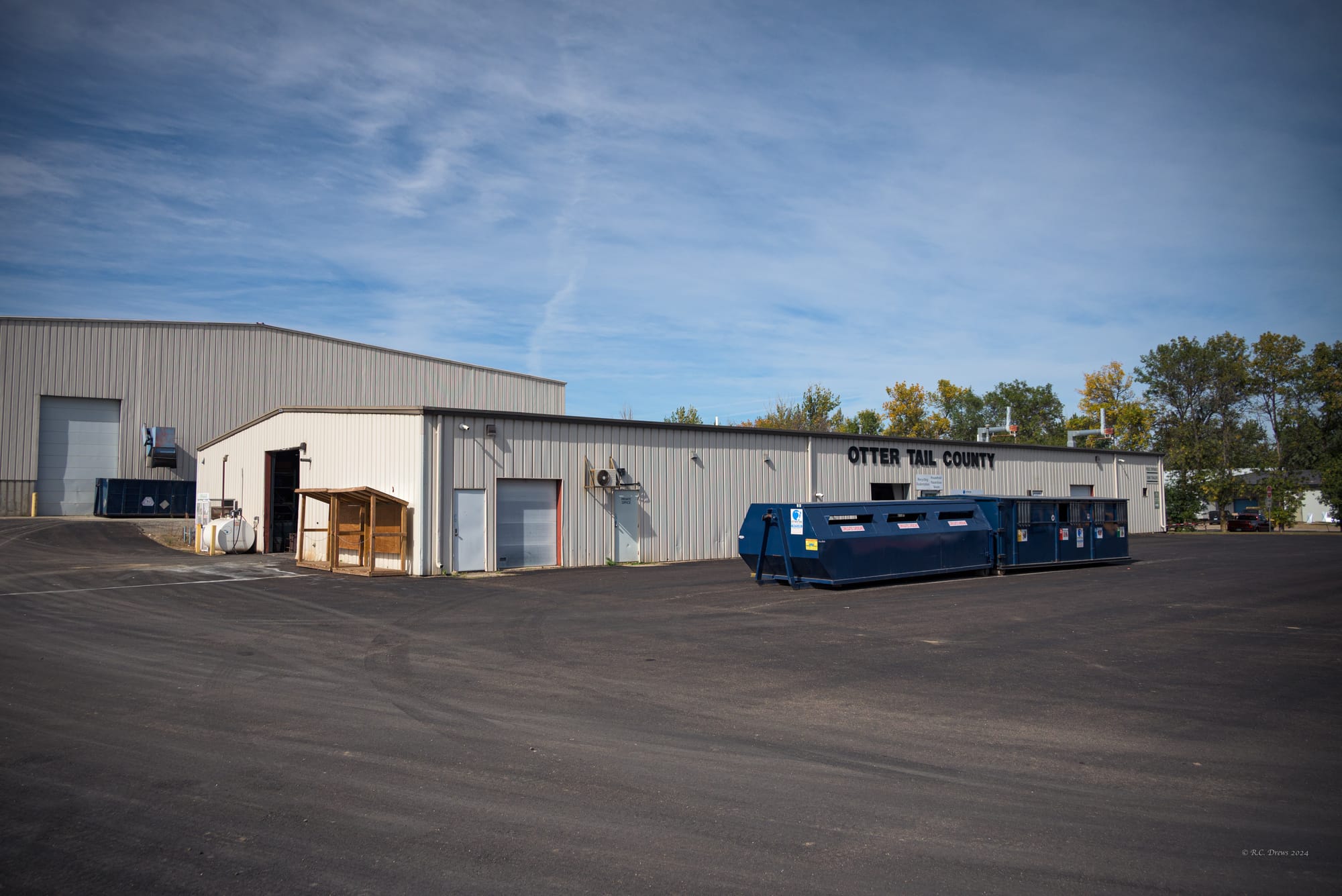 The exterior of a recycling center is pictured with several large recycling bins out front. 