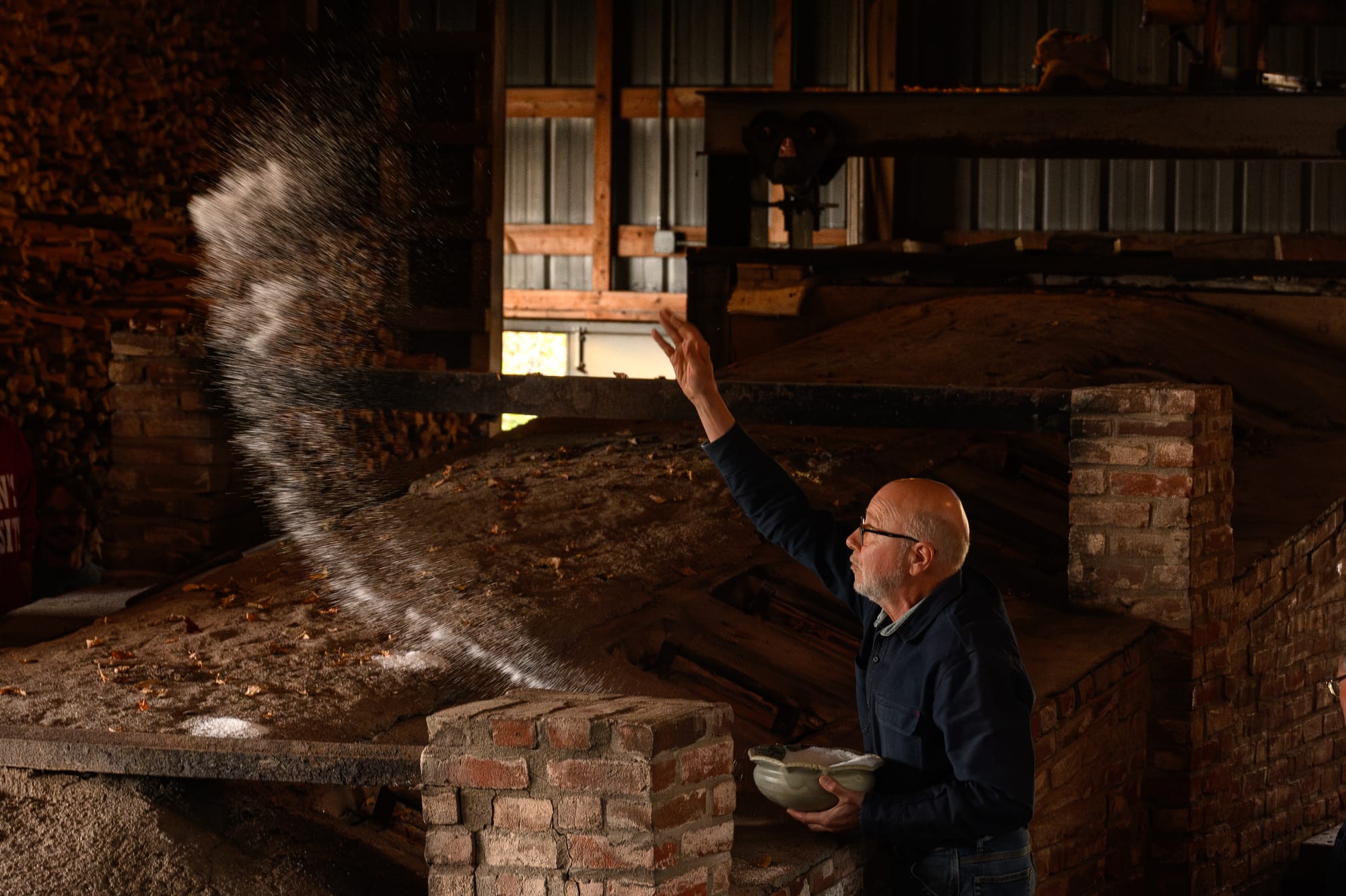 Man throws salt over a kiln to purify it. 