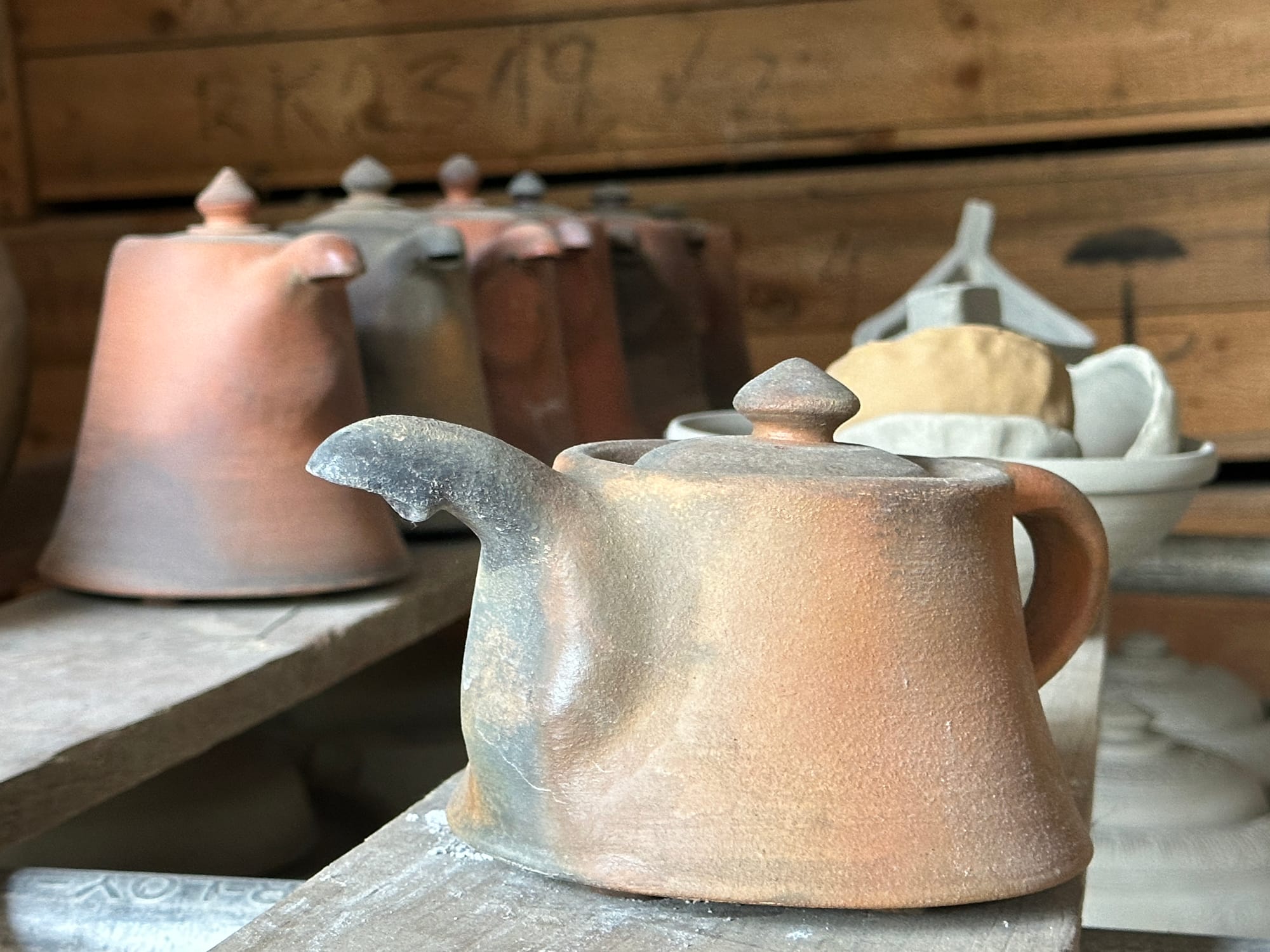 A handmade teapot sits on a shelf.