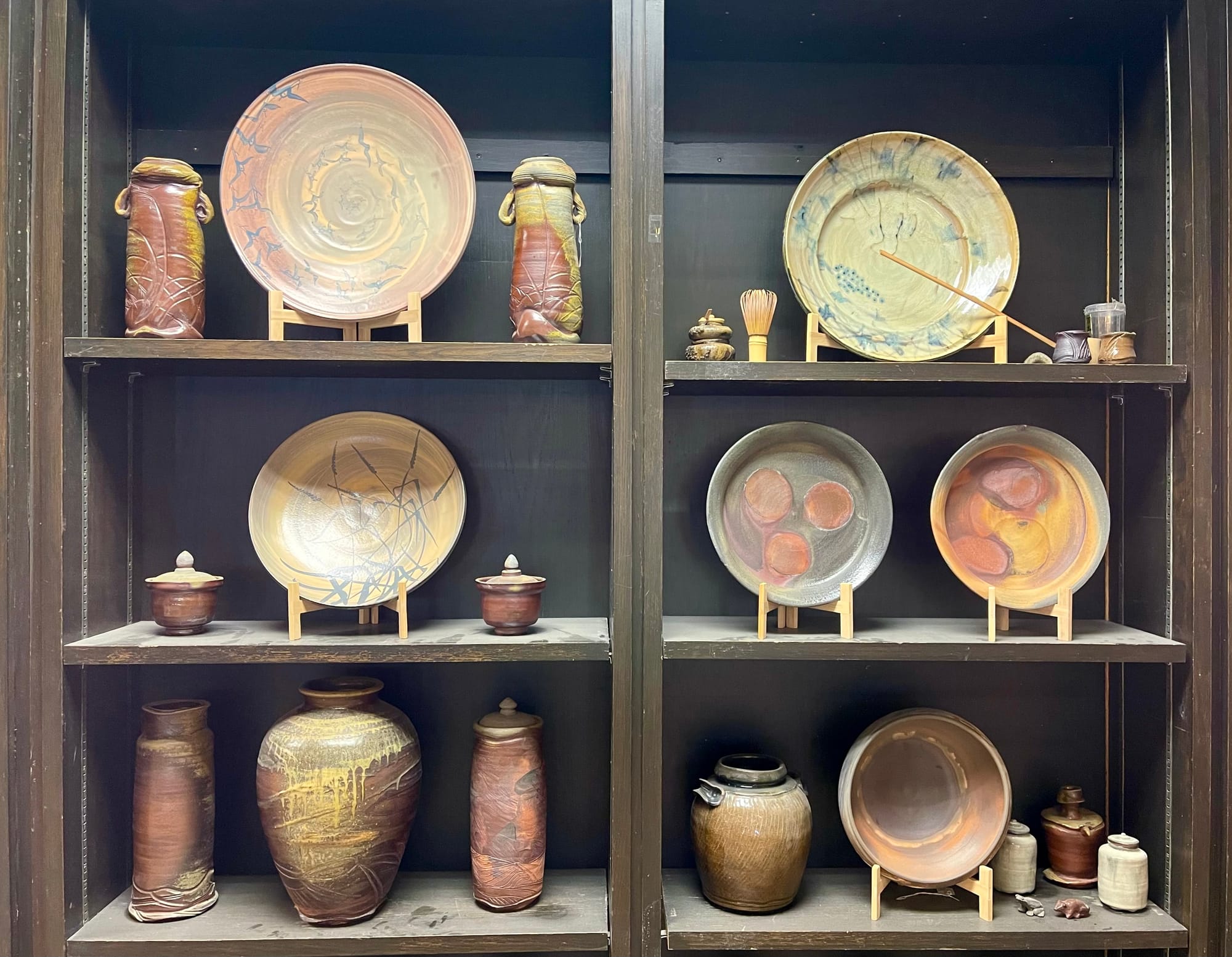 Finished pottery is displayed on studio shelves. 