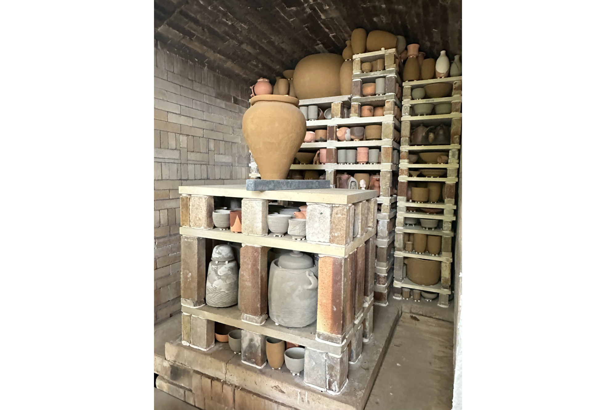 Pottery is stacked neatly in a large kiln as it waits to be fired. 