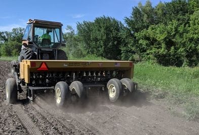 A tractor pulls a no-till drill in a field. 