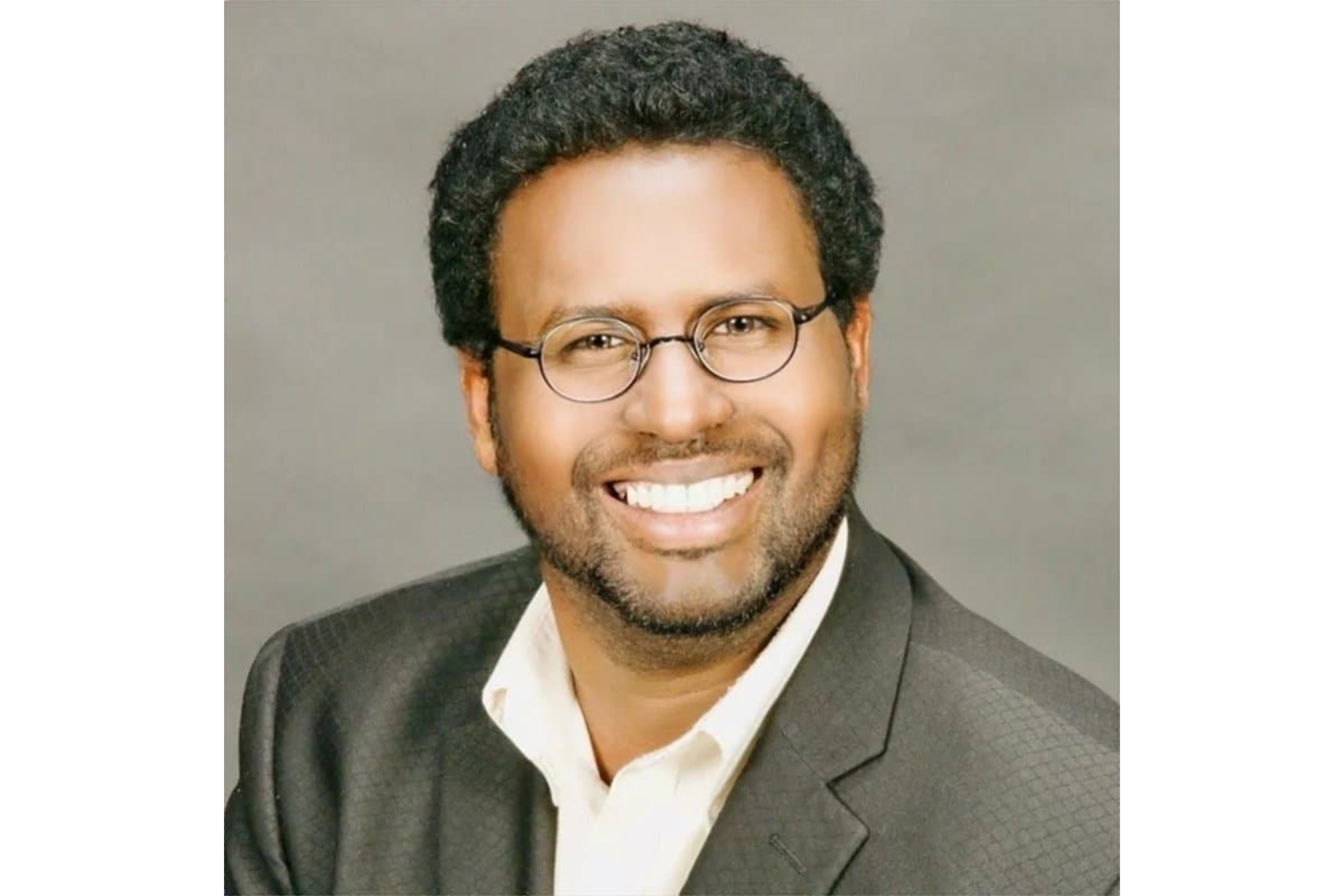 Man smiles as he poses for a portrait. 