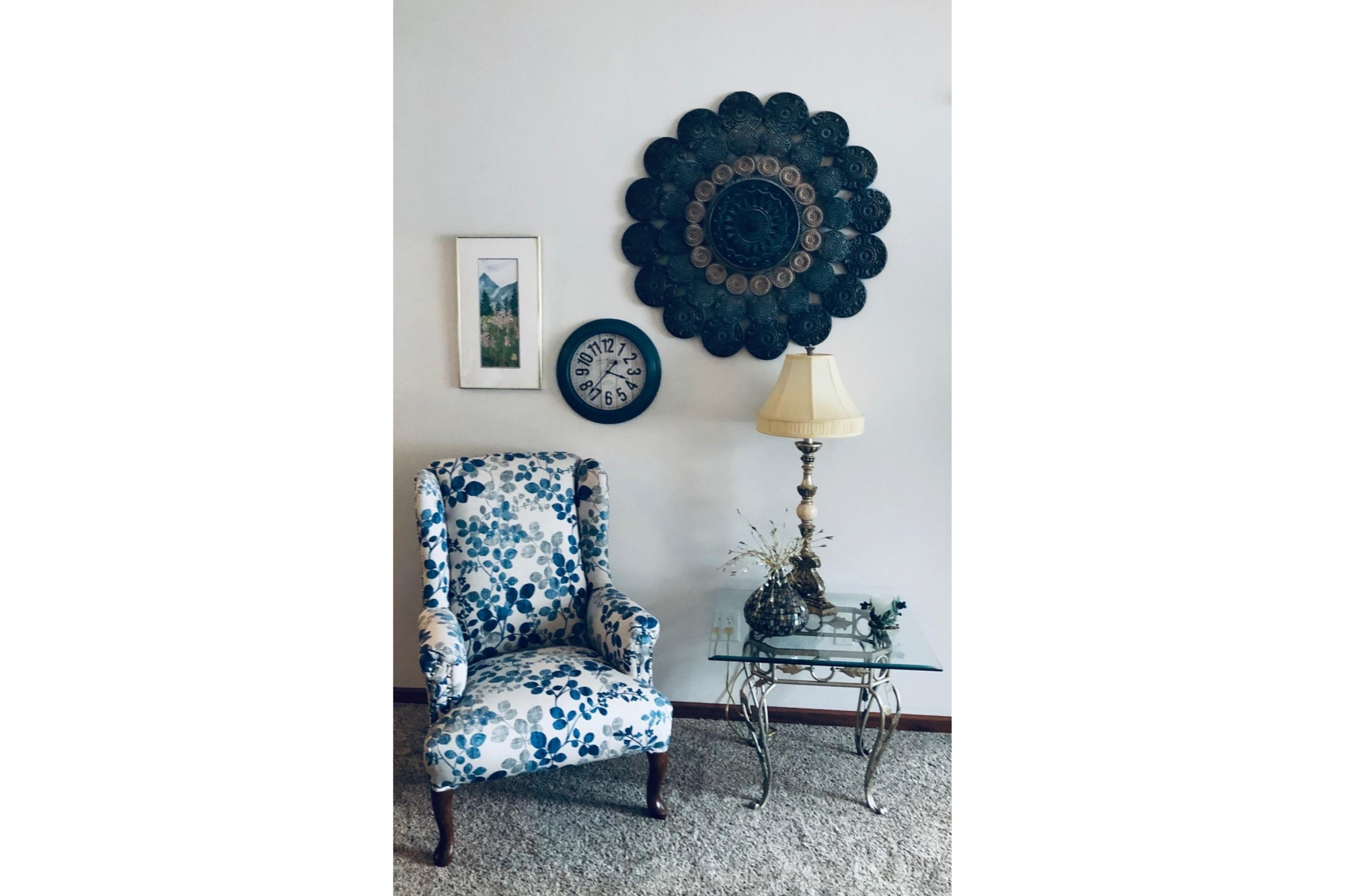 A chair, reupholstered with a white fabric that features blue florals, is pictured next to a side table. 