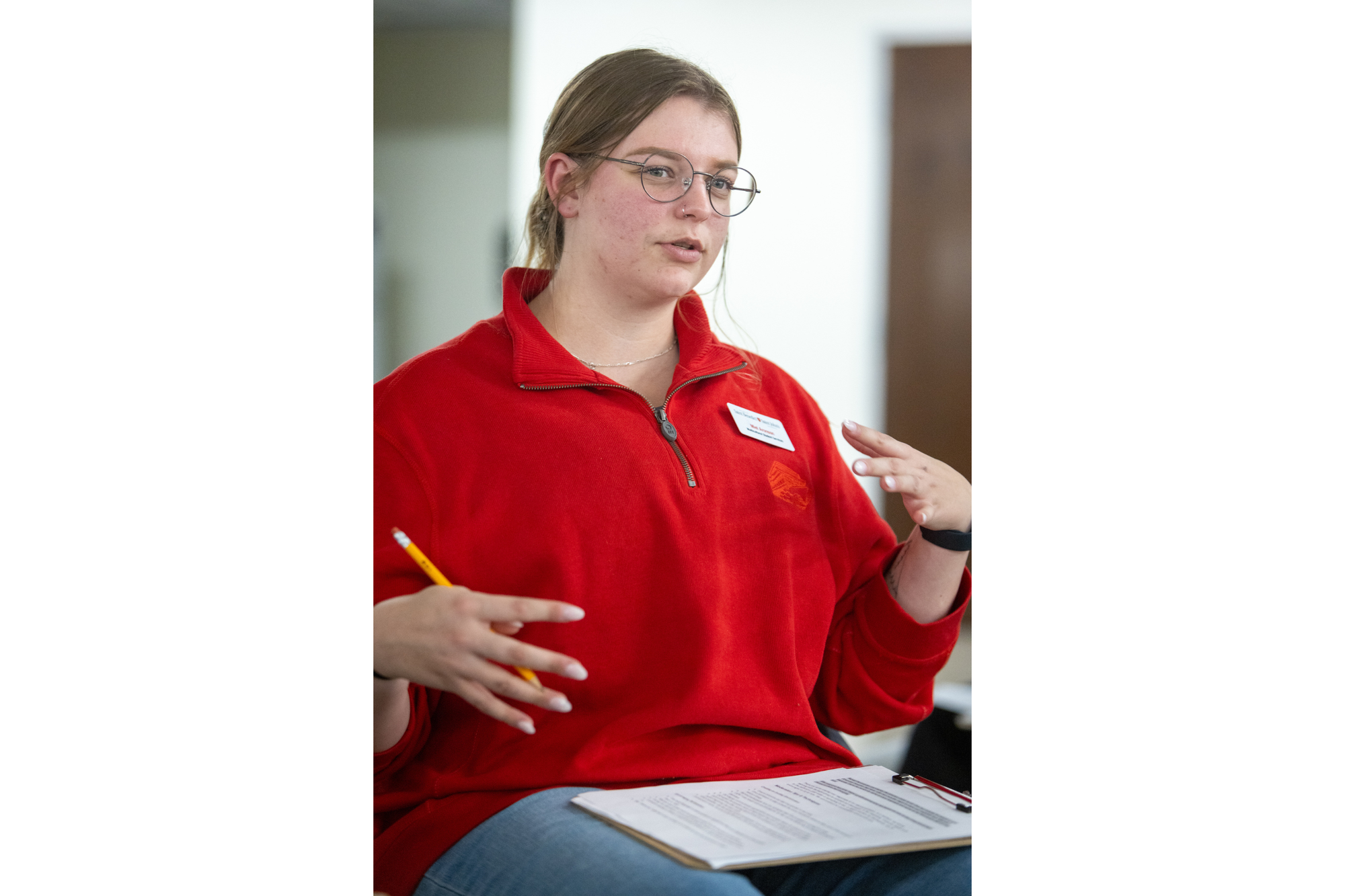 A young woman with glasses talks during a discussion event. 