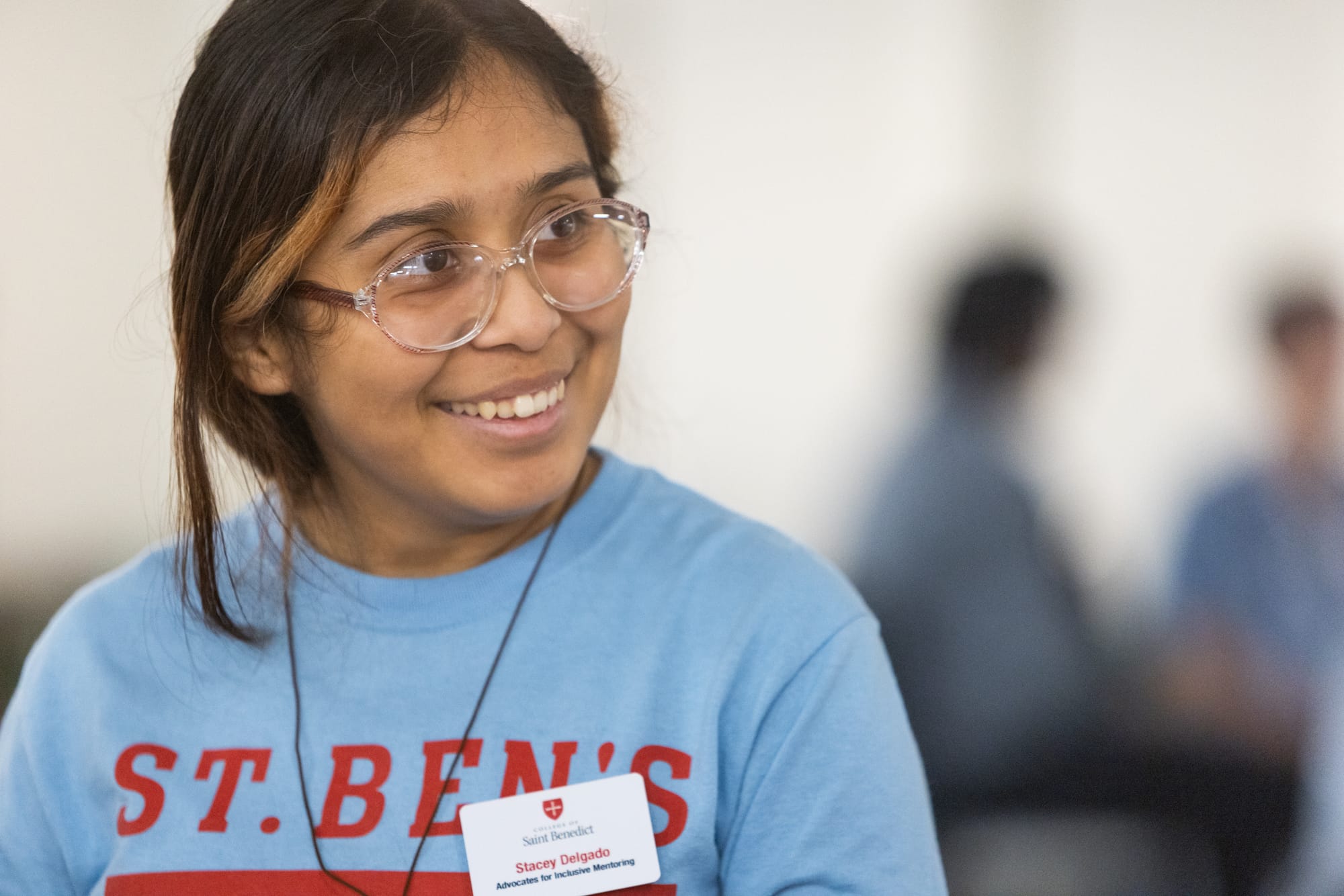 A young woman with glasses smiles during a discussion. 