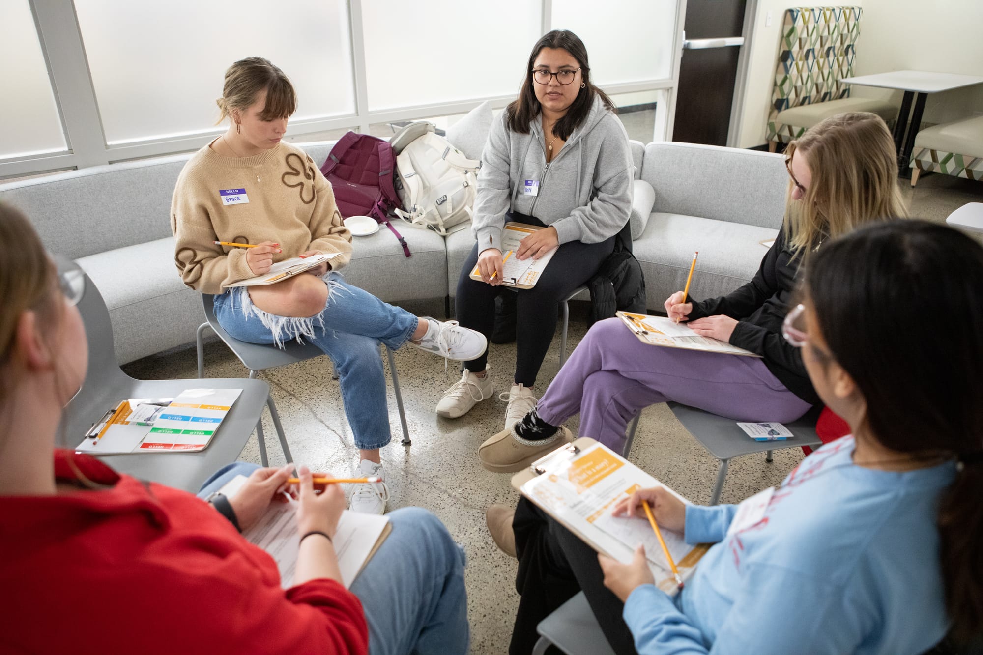 A group of young women sit in a circle during a dialogue event. 