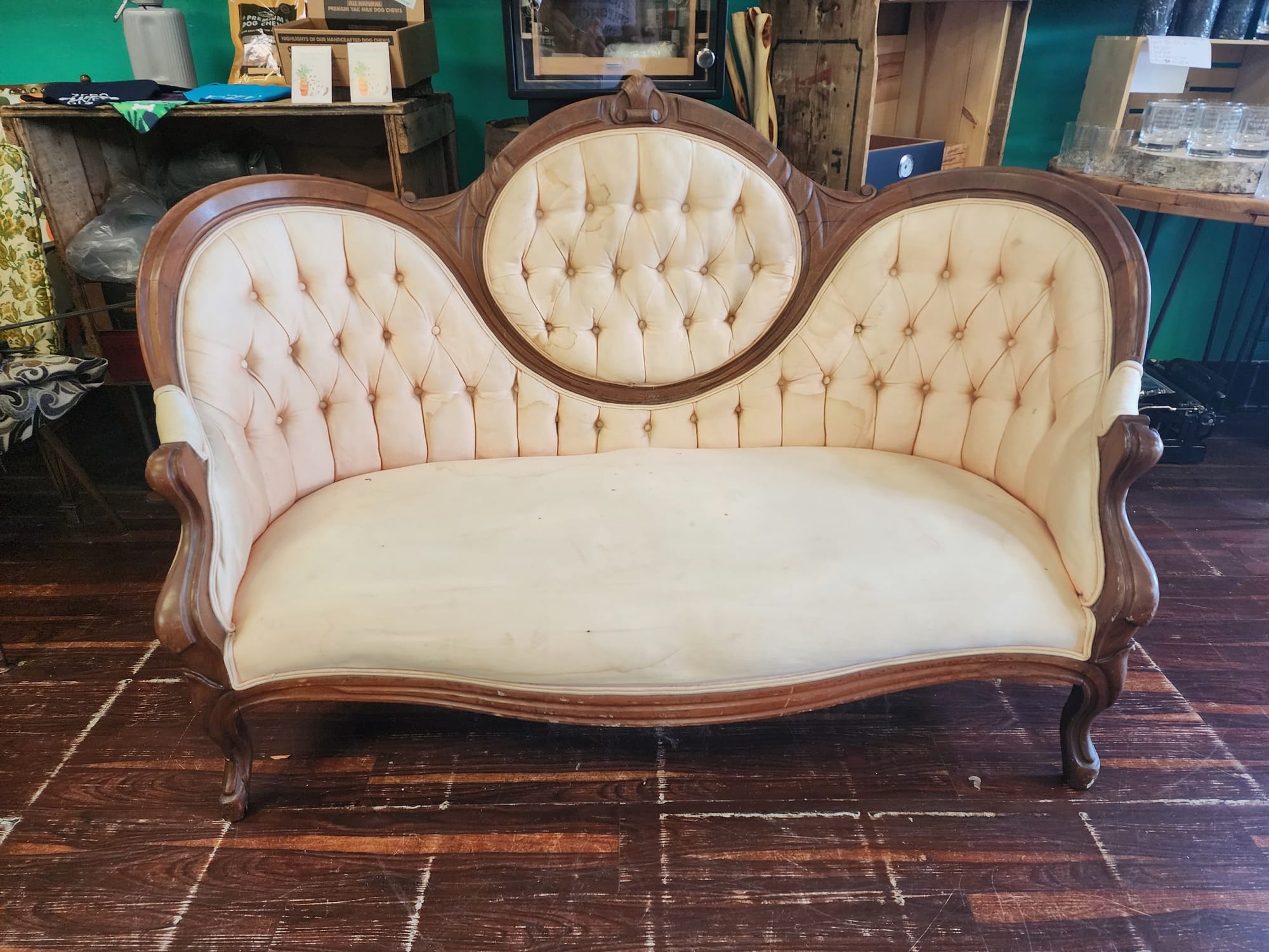 A couch in an older style that was reupholstered with cream colored fabric and buttons. 