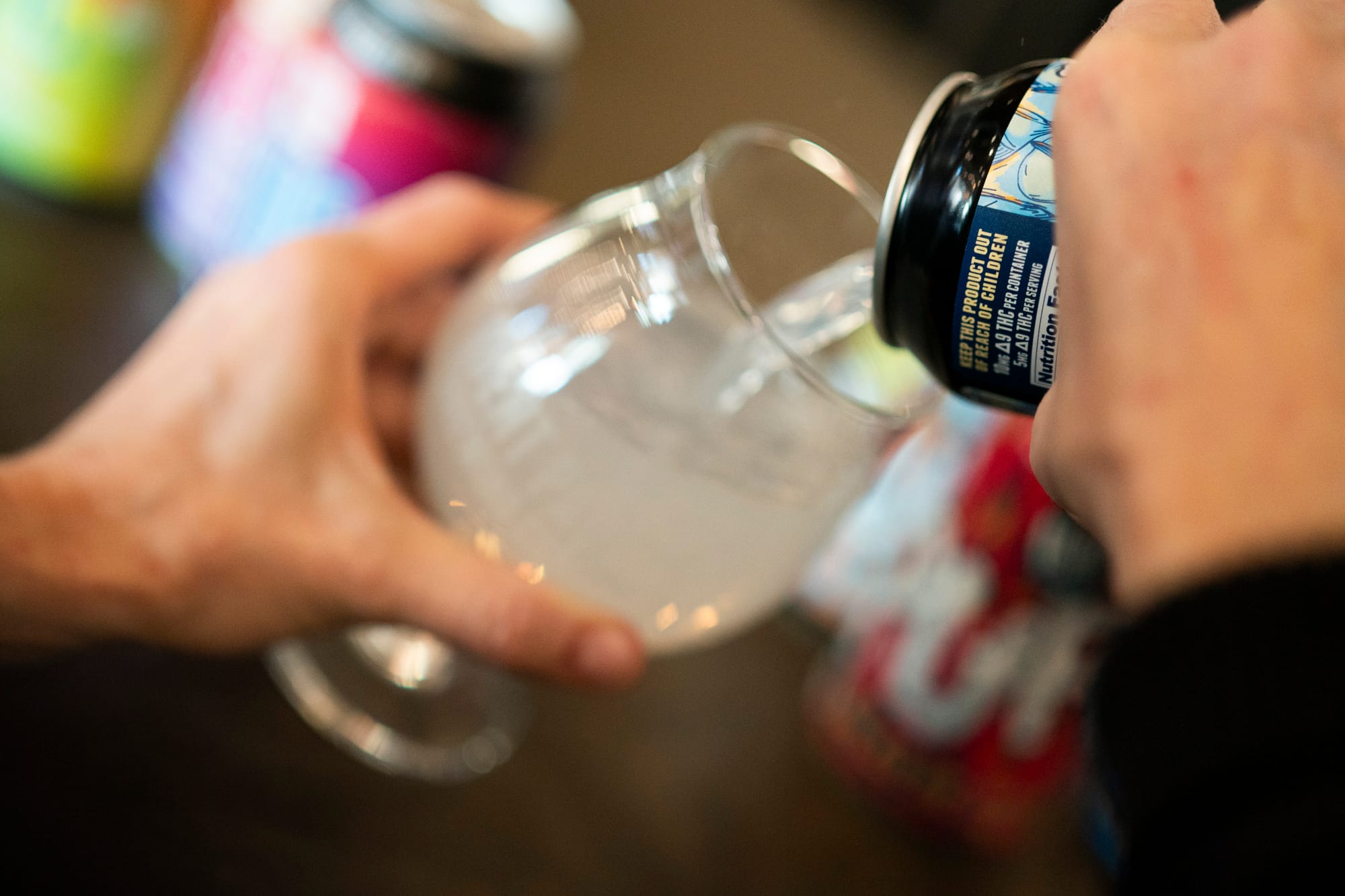 Woman pours a cannabis-infused drink into a glass.