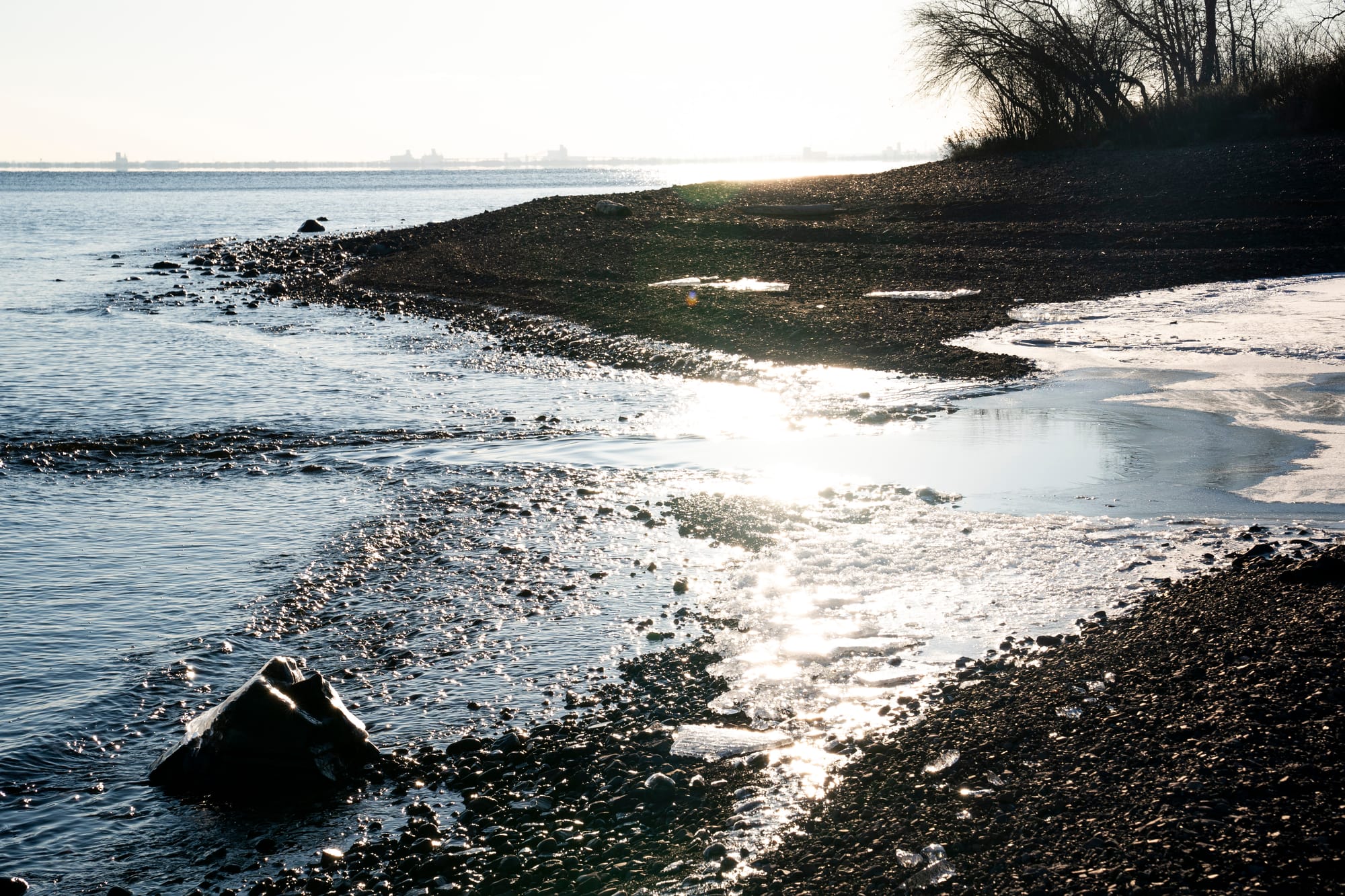 Waves lap the shoreline as ice forms on a sunny afternoon along Lake Superior in Duluth, Minn.