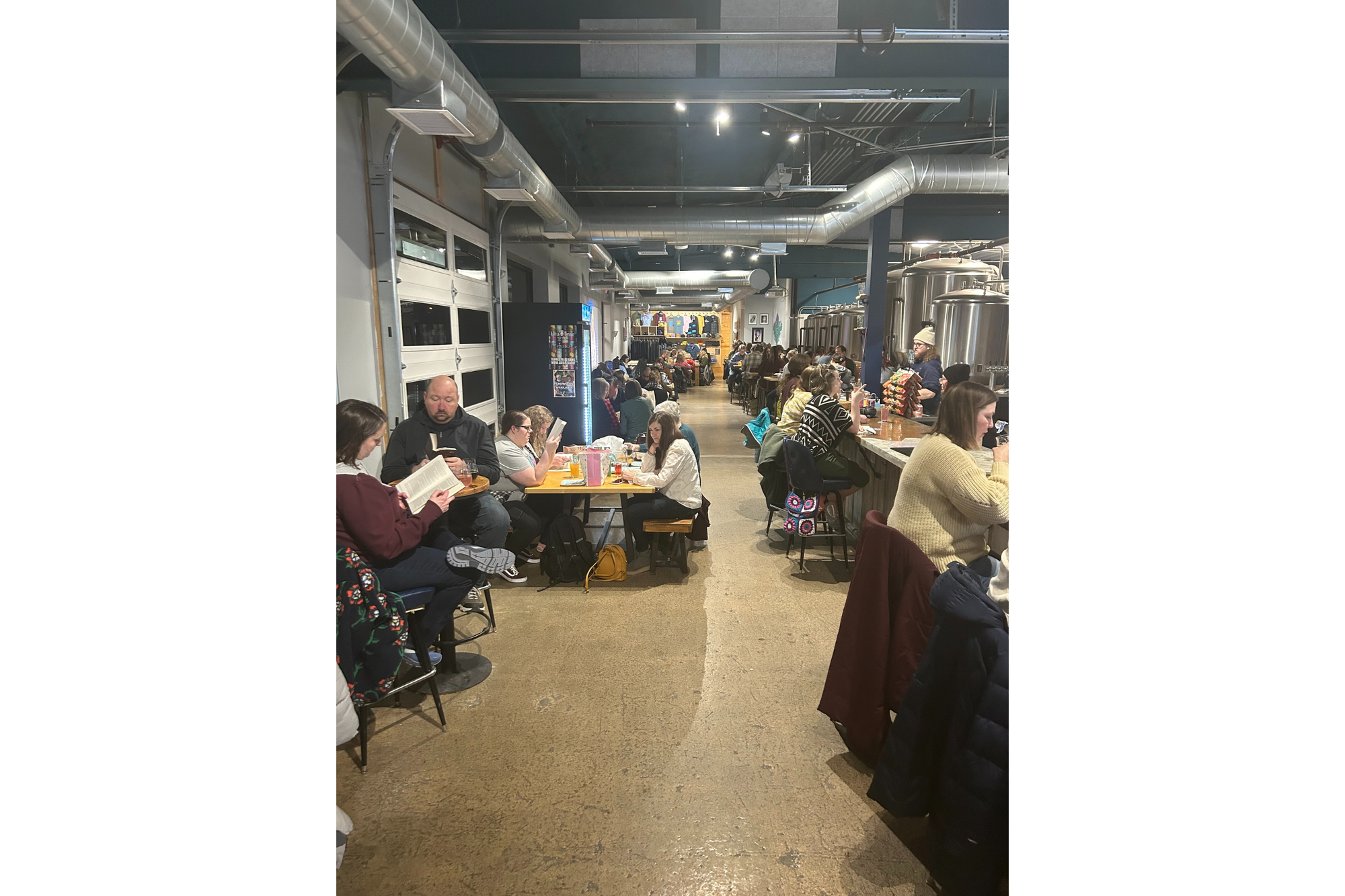 People read books in a brewery as part of a silent book club. All the seats pictured are full. 