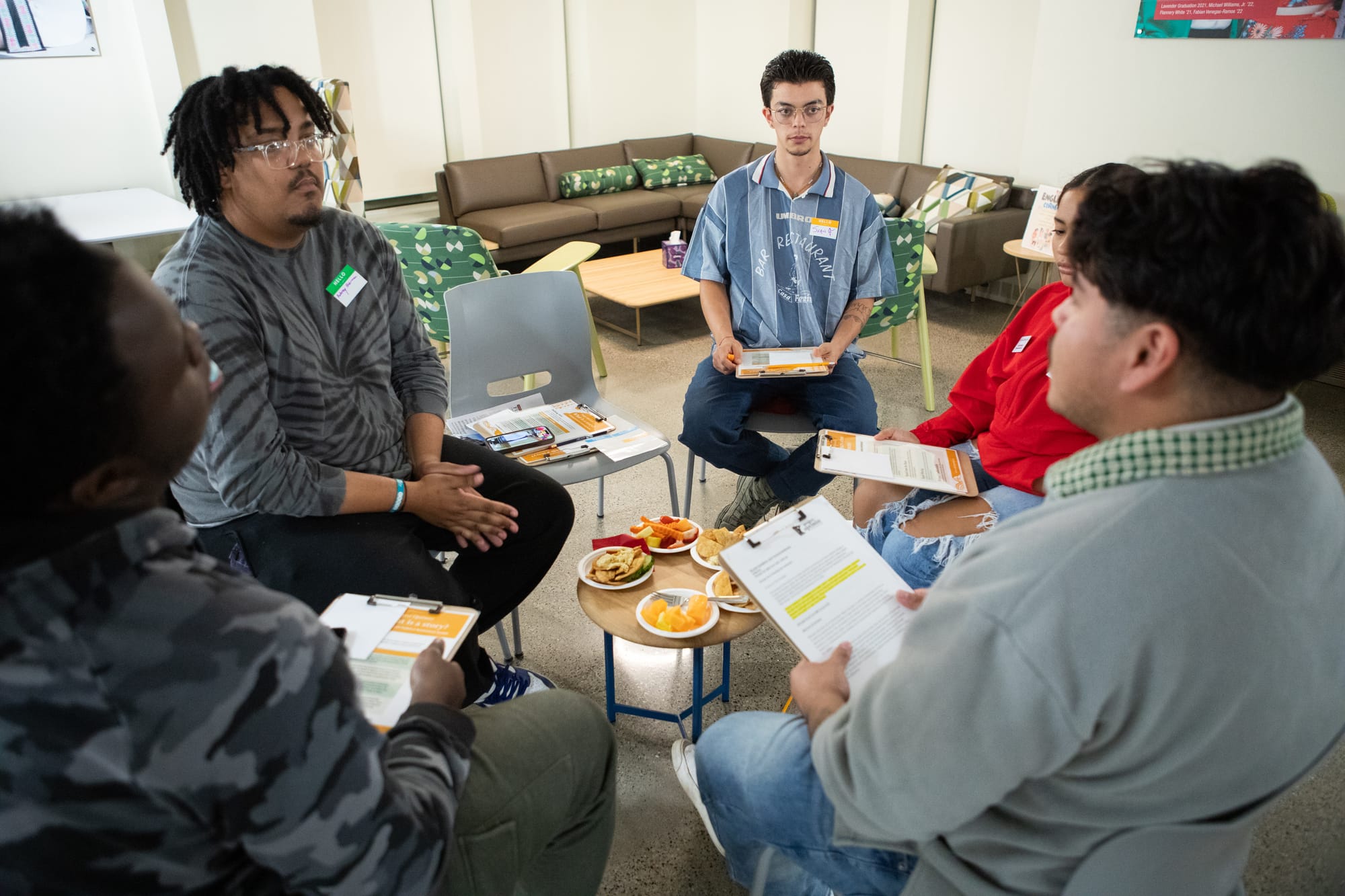 A group of students sit in a circle and listen to one of their peers share a story. 