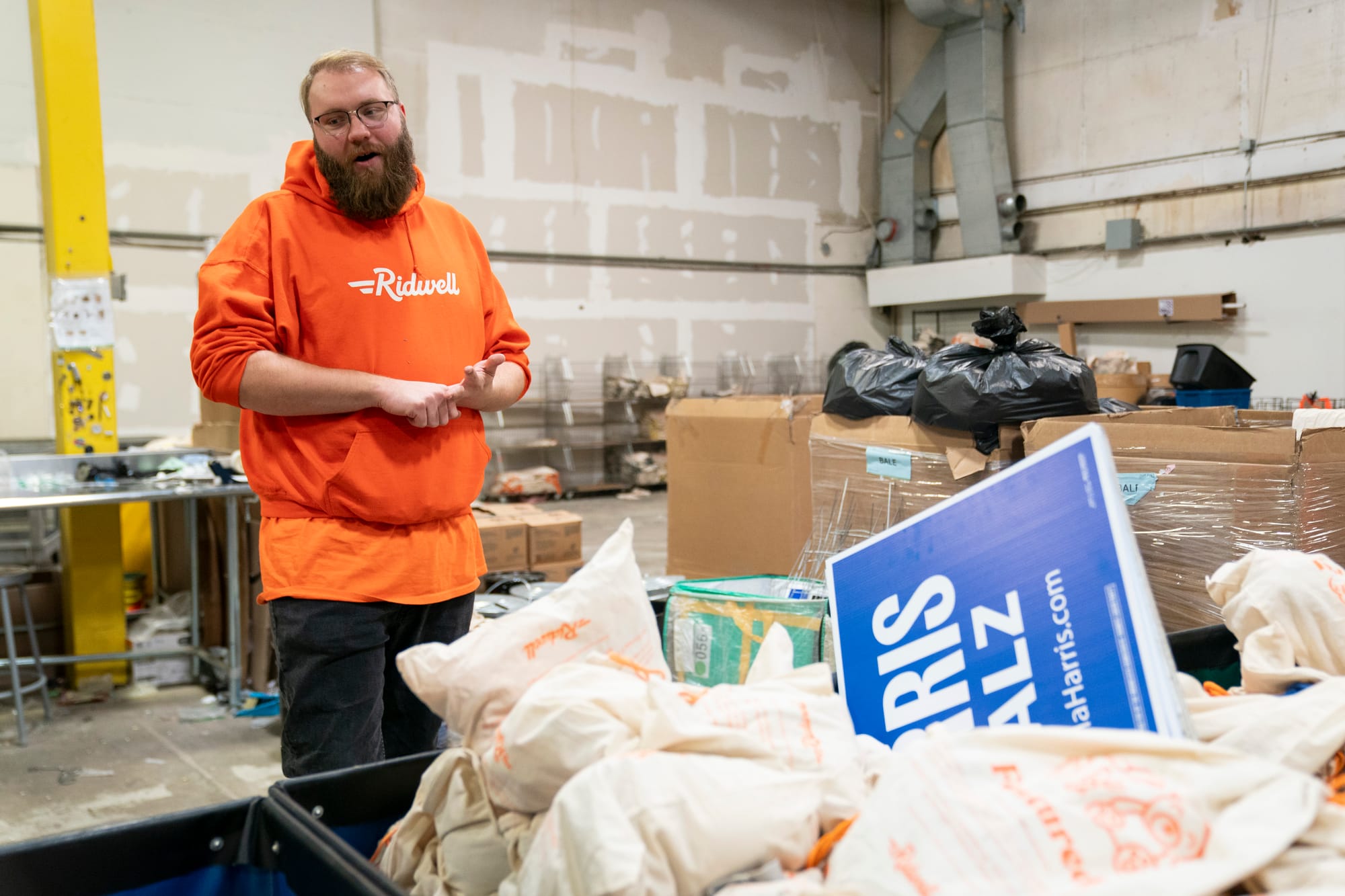 Person stands in a warehouse in front of a bin of campaign yard signs. 