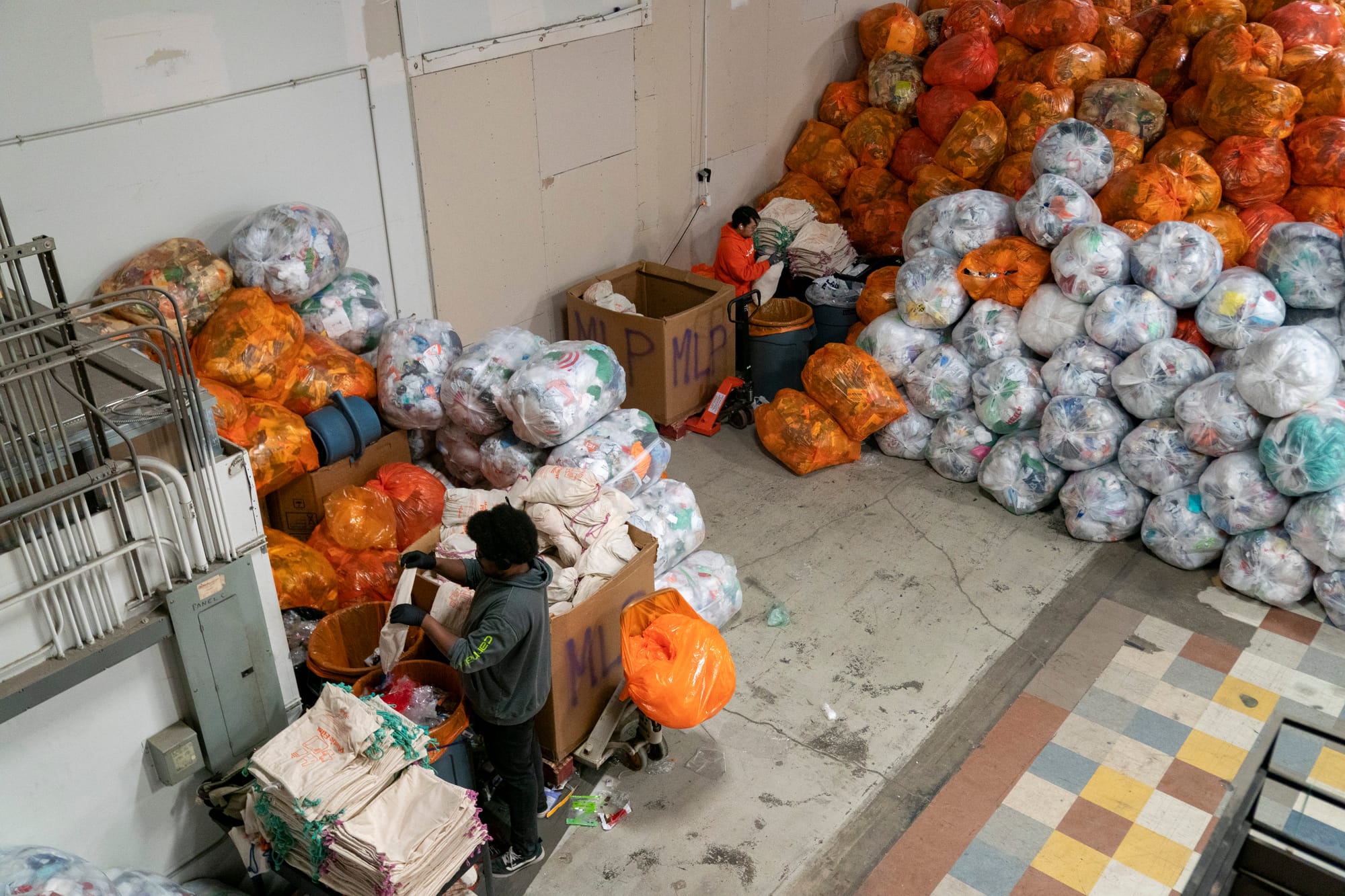 Two men process multi-layers plastics on the floor of a warehouse.