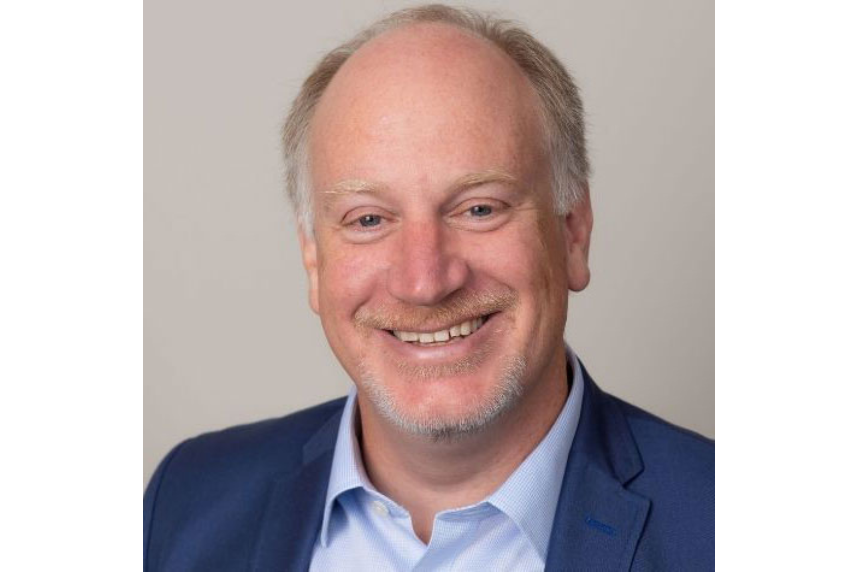 Man smiles as he poses for a portrait. 