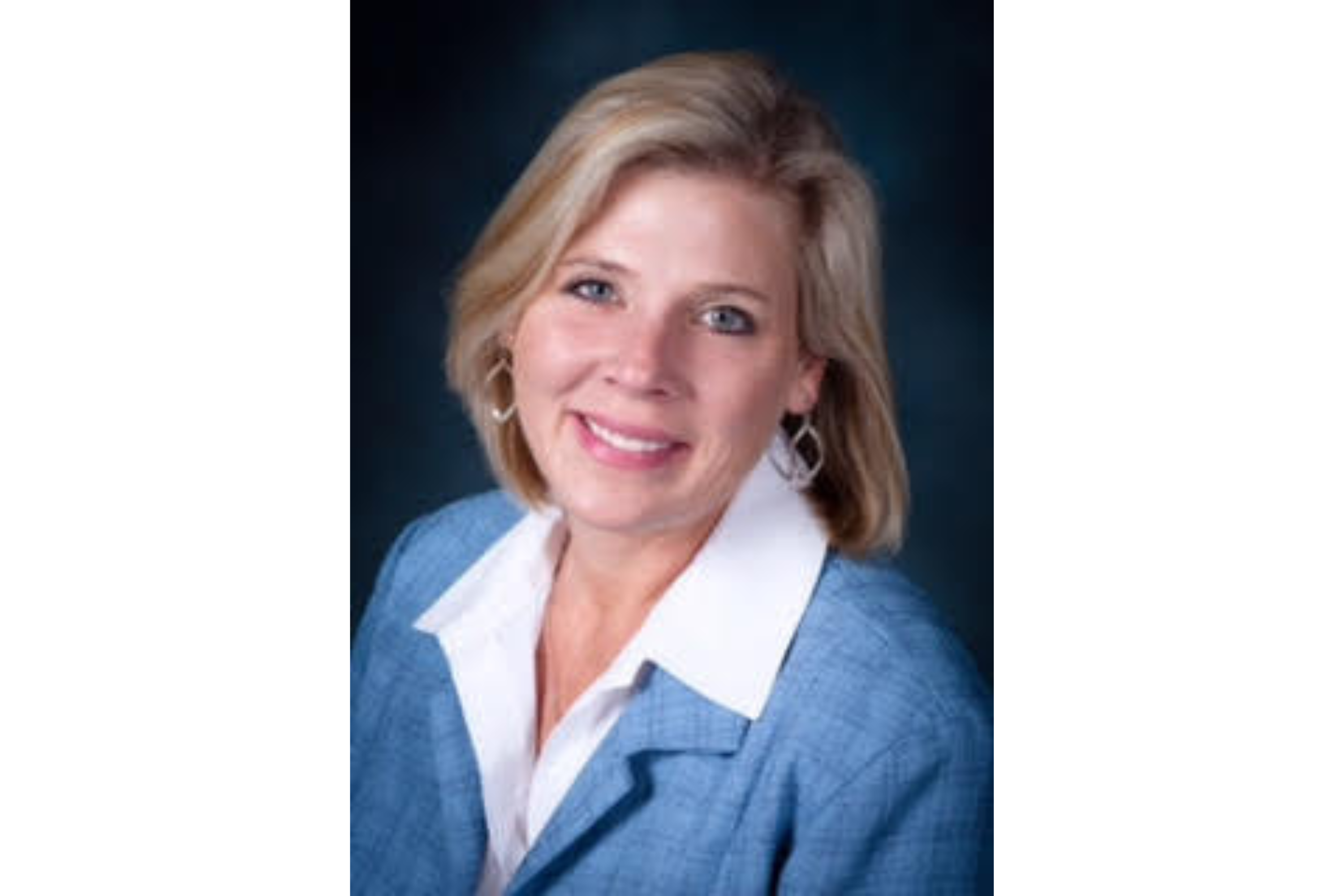 Woman poses for a professional headshot, smiles for the camera. 