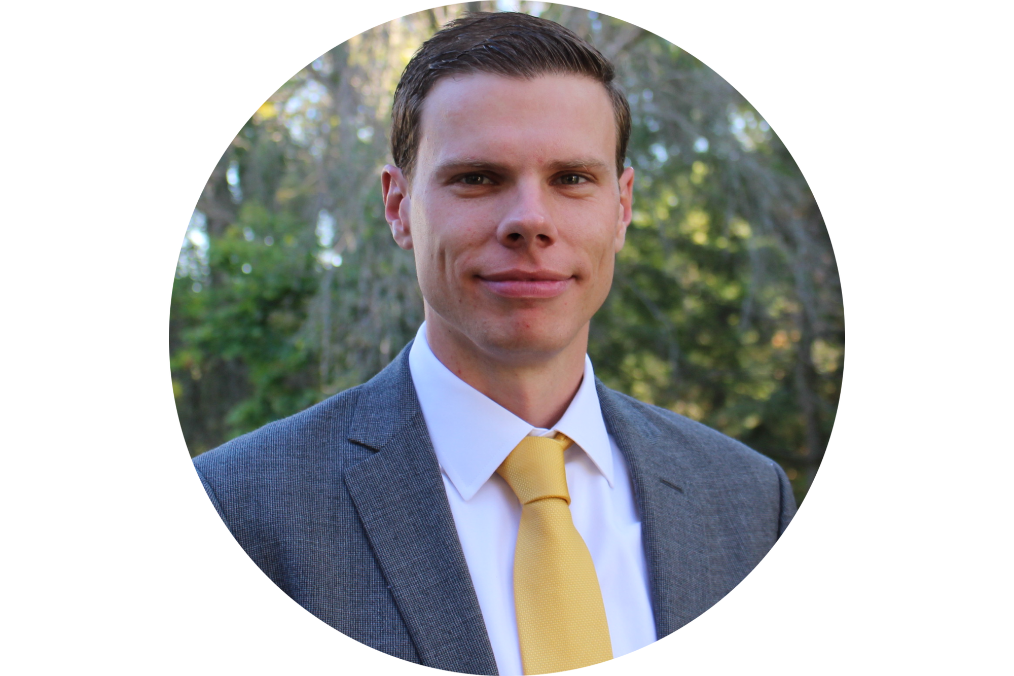 Man smiles for the camera wearing a suit and tie. 