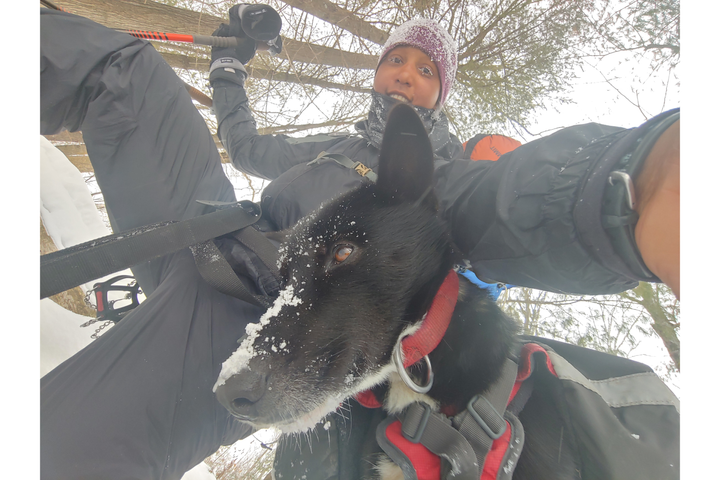 Woman poses for a photo with her dog outside in winter. 