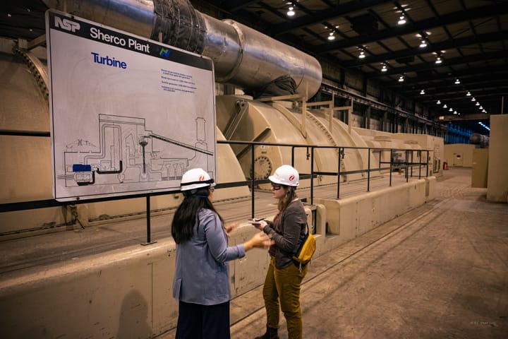 Two women with hard hats are pictured in a coal plant