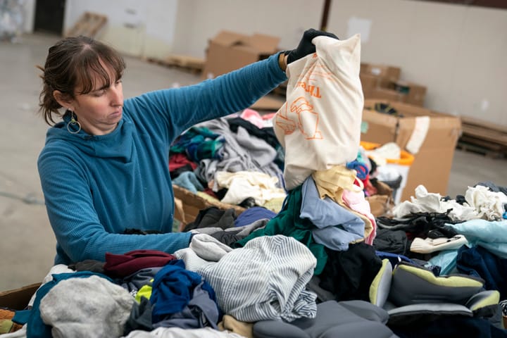 Woman empties the contents of a cloth bag into a pile to sort. 